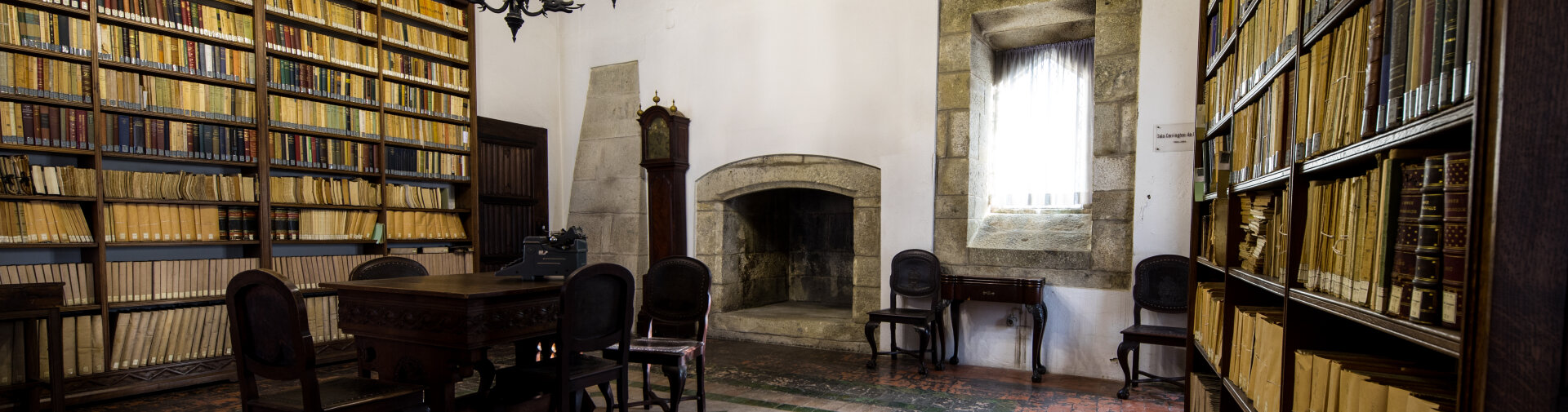 Sala do arquivo documental da Biblioteca Pública de Braga, com lareira em pedra e mobiliário de época