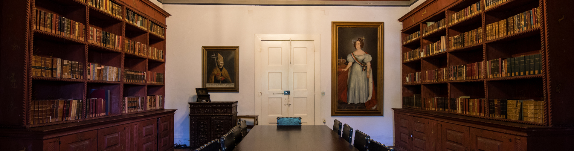 Sala de leitura histórica da Biblioteca Pública de Braga, com retratos e estantes de livro antigo